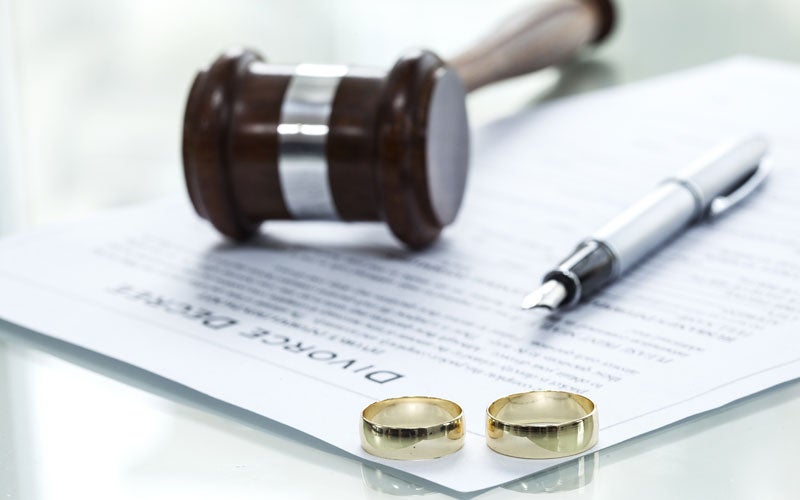 Divorce decree, gavel, pen, and two wedding rings on table