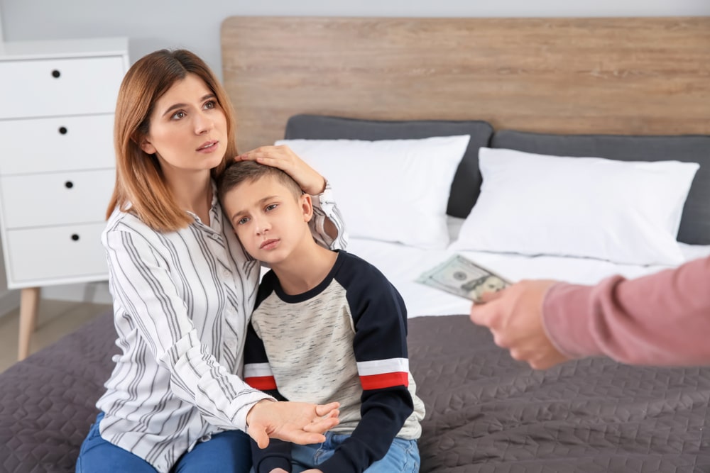 Man Handing Over Money To A Woman With A Child