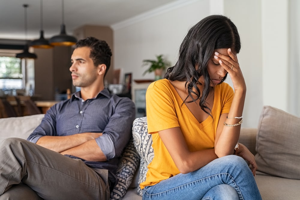 A Couple Sitting On The Couch Visibly Upset