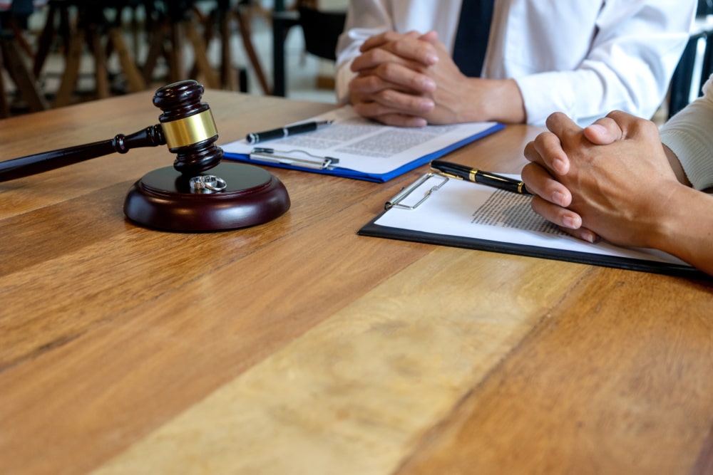 People Sitting At A Table With Legal Documents And A Judges Hammer On It