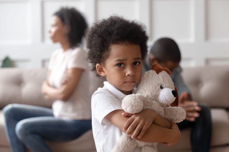 Parents Getting A Divorce An Upset Child Holding His Toy Bear With His Parents In The Background