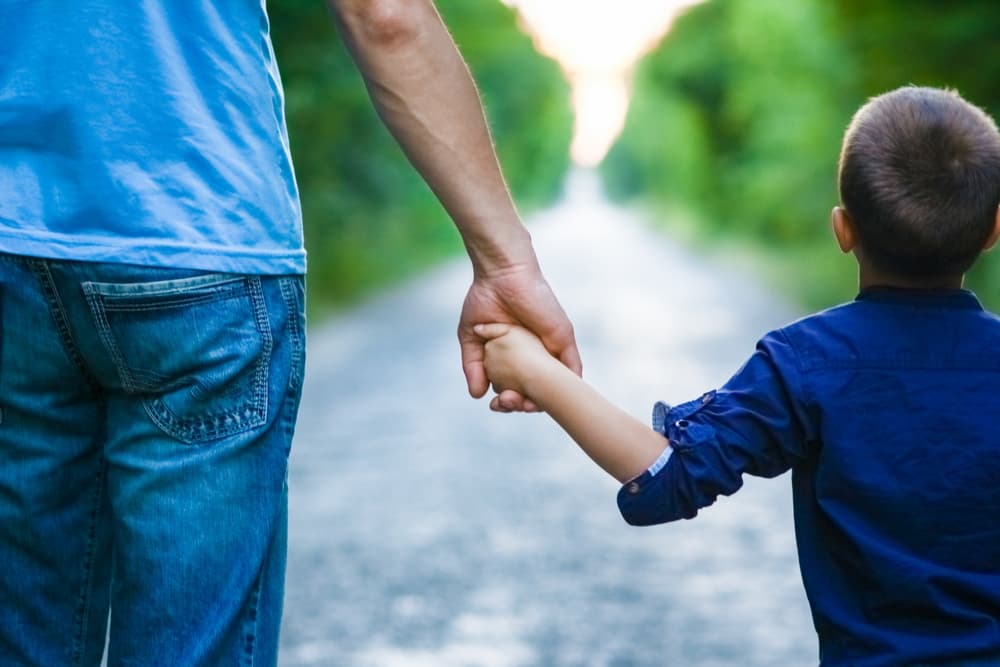 Hands of a child and a parent in nature on the road journey background