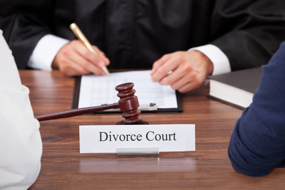 couple with judge writing at desk in divorce court