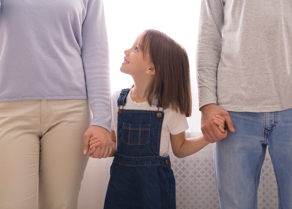 Cute Little Girl Holding Hands With Parents.