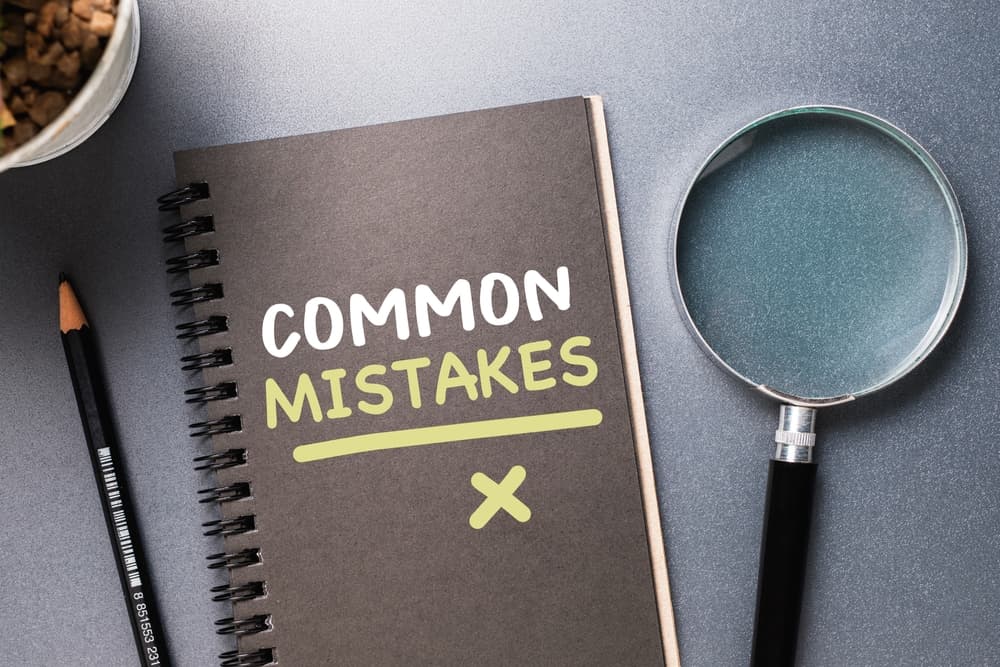 Common mistakes, text on small notepad with magnifying glass on the table.