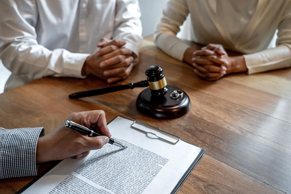 Unhappy couple having conflict, husband and wife during divorce or legal separation process with senior male lawyer