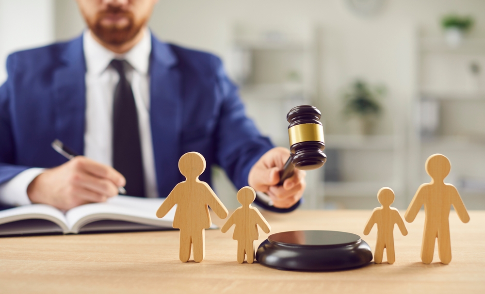Judge with gavel deciding a child custody case, with wooden family figures on the desk.
