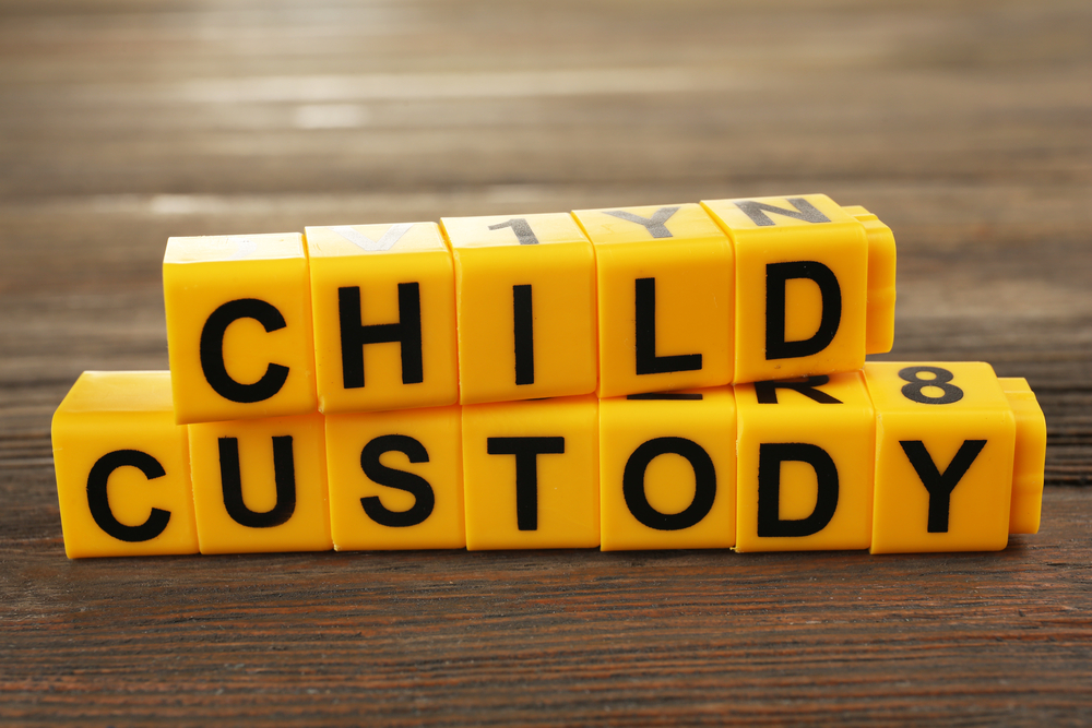 Yellow letter blocks spelling out “Child Custody” on a wooden surface.